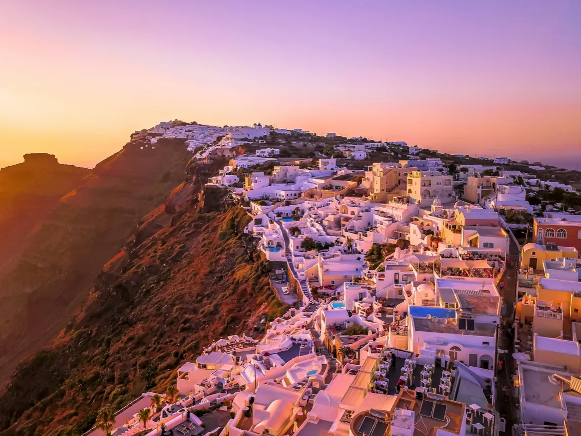 Muros encalados de Fira, en Santorini, teñidos de rosa al atardecer sobre la caldera